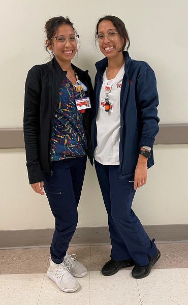 Two young female adults with dark hair pulled back wearing scrubs. Amanda Vidal is in navy scrubs on the left and Adriana Vidal is in white scrubs on the left.